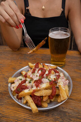 Closeup view of a woman having fried potatoes with ham, mozzarella cheese, ketchup, onion and fresh...