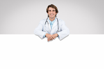 Smiling man doctor leaning on white banner, medical advertisement