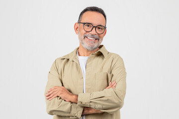 Cheerful senior man wearing stylish glasses standing with arms crossed