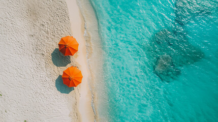 Summer and beach. Aerial view of the shore of a beach where the sea foam arrives, crystal clear turquoise water, on the white sandy shore there are two orange umbrellas