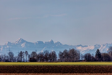 Power lines in front of the panorama of the Ammergau Alps behind a field near Schwabmünchen on a...