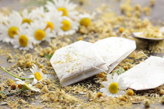 Dried chamomile herbal tea in paper teabags and flowers on black background, closeup, healing drink, natural medicine and naturopathy concept
