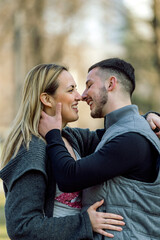 Happy couple  in love. Stylish man with a beard and a beautiful girl on the autumn sunny day kissing. Portrait of a happy young couple enjoying a day in the park together .