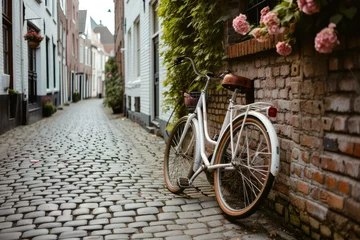 Papier Peint photo Vélo A white bicycle is parked on a cobblestone street next to a brick wall