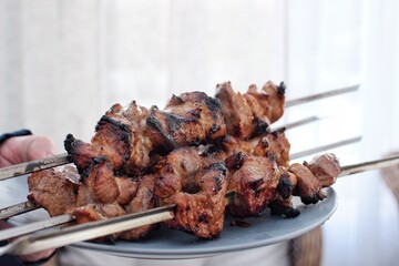 Barbecued meat on skewers on a plate.