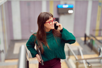busy young professional woman talking on the cell phone leaving the subway