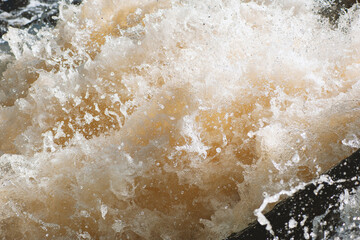 Natural background of rough water foam splashing in a river.