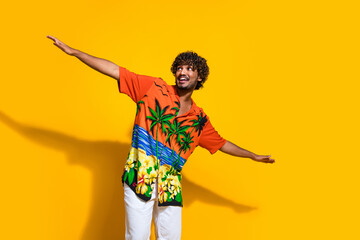 Fototapeta na wymiar Portrait of impressed guy wear hawaii print shirt arms like wings look at proposition empty space isolated on yellow color background