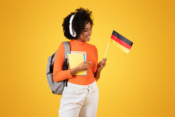 Happy young student with curly hair looking at a German flag