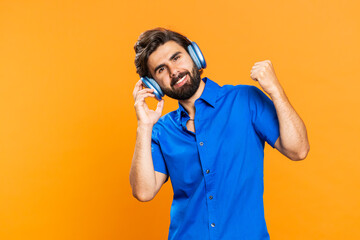 Happy man in headphones listening music and dancing disco fooling around having fun expressive...