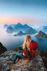 Woman traveler hiking in Norway girl backpacker relaxing on mountain cliff edge in Lofoten islands...