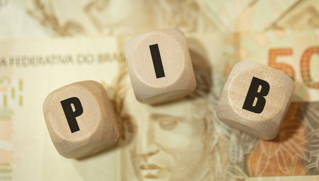 A abrevia&ccedil;&atilde;o PIB para Produto Interno Bruto escrita em dados de madeira na linguagem Portugu&ecirc;s do Brasil. Notas de 50 Reais do Real Brasileiro na composi&ccedil;&atilde;o.