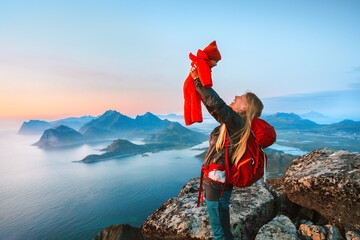 Family vacations in Norway  - mother lifting up infant baby outdoor travel in Lofoten islands active healthy lifestyle happy woman with child on mountain top enjoying landscape, Mothers day holiday - 757475150