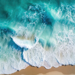 Overhead drone shot of blue waves crashing onto the sandy beach shore