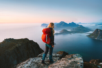 Woman hiking in Norway solo traveler on mountain cliff edge in Lofoten islands tourist with backpack traveling outdoor alone healthy lifestyle summer vacations adventure eco tourism - obrazy, fototapety, plakaty