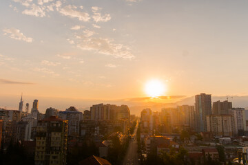 View of dramatic sunrise sky with the rising sun over the city of Batumi, Georgia. City is slowly awakening. Urban, early morning, summer and cityscape concept