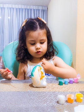Ni&ntilde;a feliz y concentrada jugando con pinturas y temperas