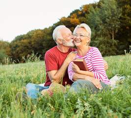 woman man outdoor senior couple happy lifestyle retirement together smiling love reading nature book sitting grass - 757483743
