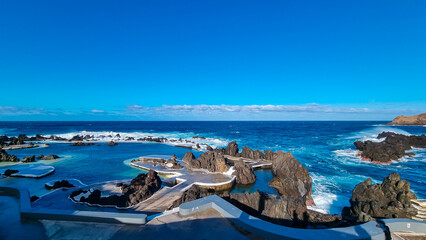 Natural lava pools with panoramic view of volcanic rock formation Ilheu Mole in coastal town Porto...