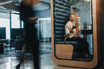 Successful young businesswoman smiling while working in a privacy booth