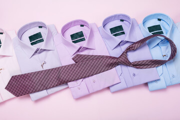Multi-colored men's shirts and tie on a pink background, concept on the topic of matching a tie, top view