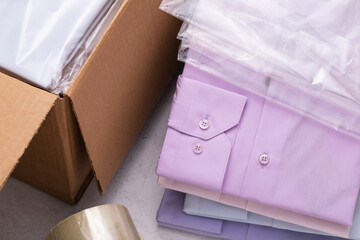 Open cardboard box, folded shirts and transparent bags, concept on the packaging of goods before sending to the customer