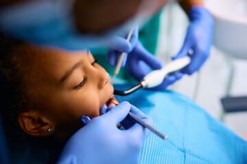 Black little girl during dental procedure at dentist's office.