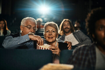 Smiling senior couple watching a movie in the cinema