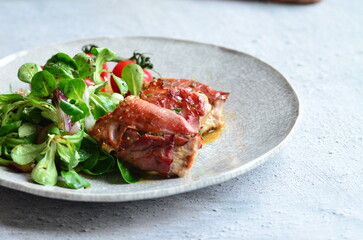 beautiful background of food served on a rustic plate, italian cuisine, grilled veal meat with parma ham and sage, mixed salad, close up view,