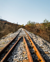 Obraz premium Railway track in the nature, mountains and yellow trees, gravel on the ground