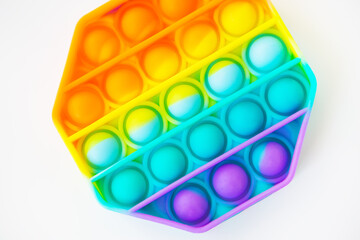 A colorful pop it fidget toy against a white background. The hexagonal toy has vibrant rainbow...