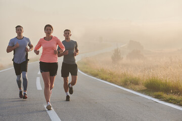 A group of friends, athletes, and joggers embrace the early morning hours as they run through the...