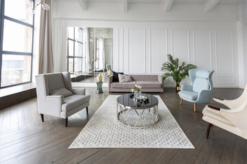 Modern luxury stylish apartment interior in pastel colors. a very bright room with huge windows filled with daylight. white walls, wooden parquet floors and a dark marble fireplace
