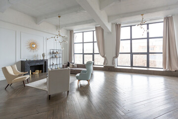 Modern luxury stylish apartment interior in pastel colors. a very bright room with huge windows filled with daylight. white walls, wooden parquet floors and a dark marble fireplace
