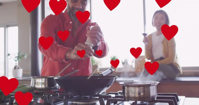 Animation of hearts over diverse couple embracing cooking in kitchen