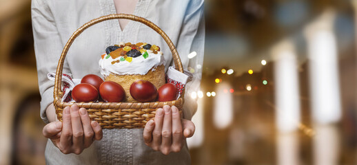 Easter cake and eggs in a basket held by a woman.