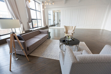 Modern luxury stylish apartment interior in pastel colors. a very bright room with huge windows filled with daylight. white walls, wooden parquet floors and a dark marble fireplace