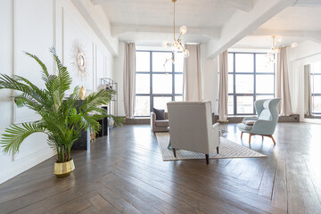 Modern luxury stylish apartment interior in pastel colors. a very bright room with huge windows filled with daylight. white walls, wooden parquet floors and a dark marble fireplace