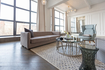 Modern luxury stylish apartment interior in pastel colors. a very bright room with huge windows filled with daylight. white walls, wooden parquet floors and a dark marble fireplace