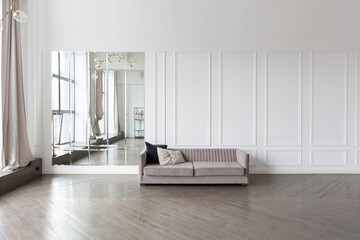 Modern luxury stylish apartment interior in pastel colors. a very bright room with huge windows filled with daylight. white walls, wooden parquet floors and a dark marble fireplace