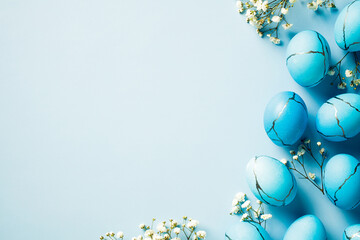 Blue marble Easter eggs with flowers on pastel blue background