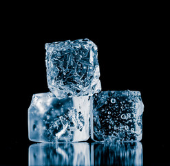 A group of three ice cubes, isolated on a black background.