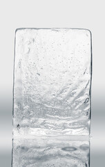Crystal clear natural ice block in light tones on a reflective surface.