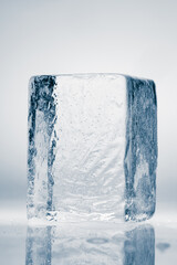 Natural crystal clear melting single ice cube on a white background with reflection.