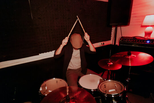 Unrecognizable male drummer performing on studio with enthusiasm