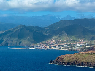 Obraz premium Panoramic view of coastal village Canical at majestic Atlantic Ocean coastline seen from Ponta de Sao Lourenco peninsula, Madeira island, Portugal, Europe. Hiking trail along steep rocky rugged cliffs