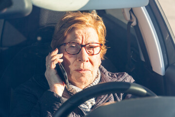 Elderly woman committing a traffic violation, talking on the phone driving a car.