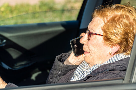 Elderly woman committing a traffic violation, talking on the phone driving a car.