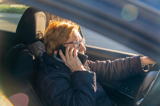 Elderly woman committing a traffic violation, talking on the phone driving a car.