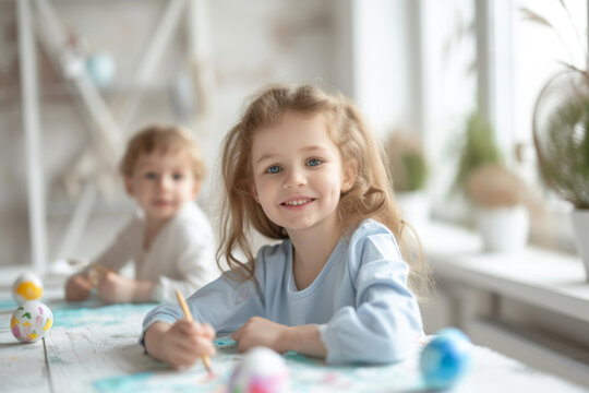 Portrait of smiling girl 4 years old with blue eyes plays at home, decorated, painting Easter eggs, have fun in light room. Happy childhood. Education. Adorable kids spending time in kindergarten